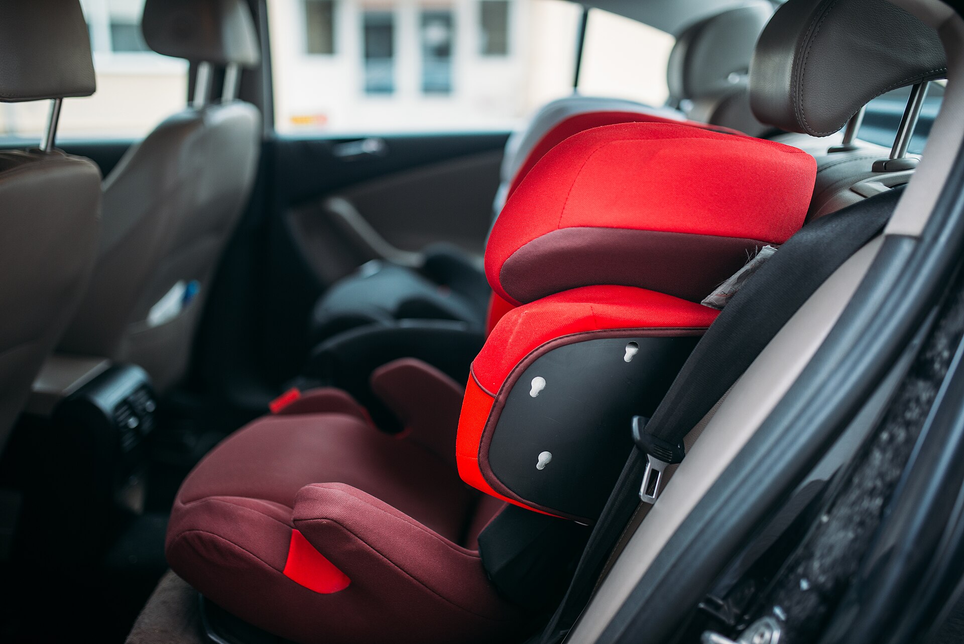 A high-backed child car seat fitted in the rear seat of a car.