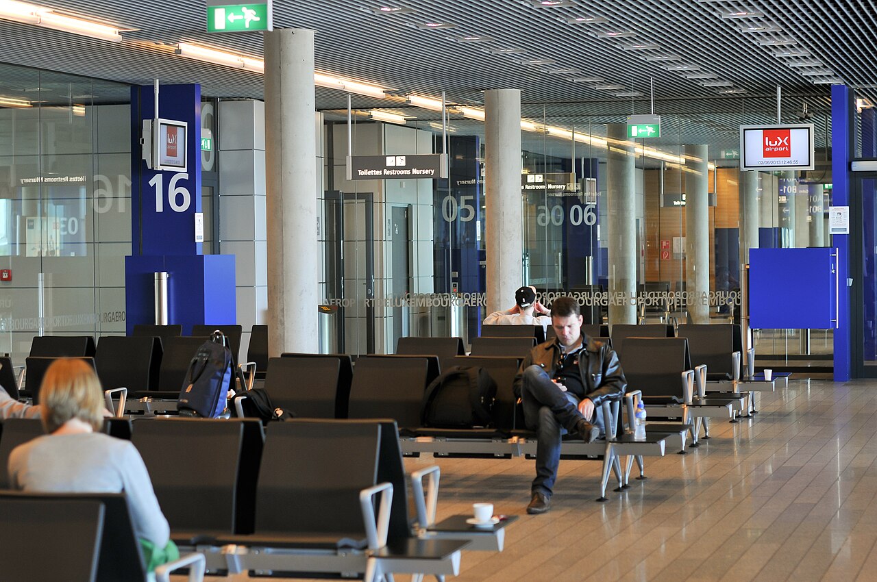 Waiting area of an airport departure hall with rows of seats and daylight from above