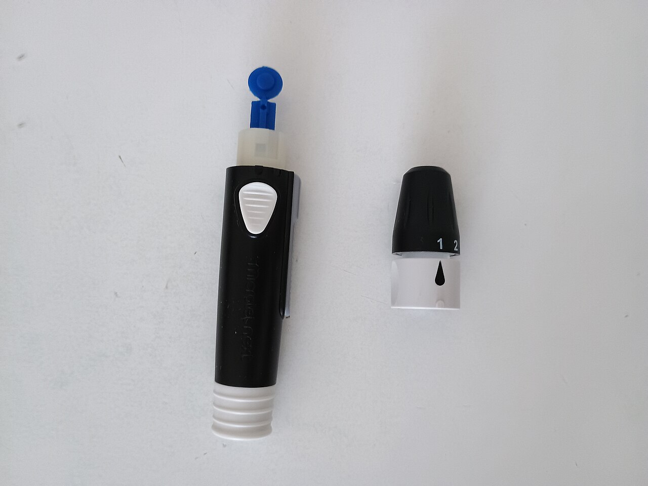 Glucose meter and its accessories arranged on a flat surface