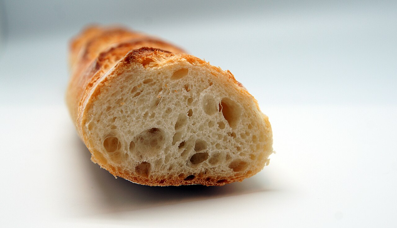 Cut baguette showing the irregular open crumb inside the crust