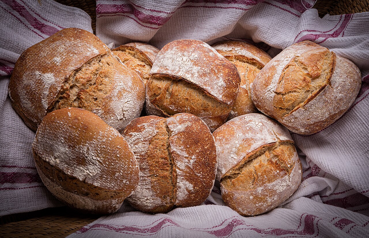 Round home-baked sourdough loaf with a scored, darkened crust