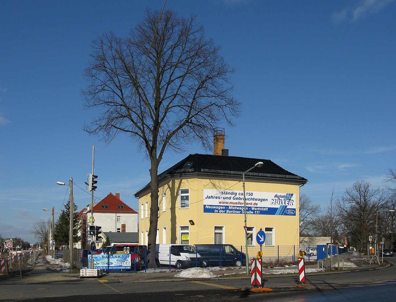 Zgrada autosalona sa staklenom fasadom i rabljenim automobilima parkiranim ispred, u Berlinu