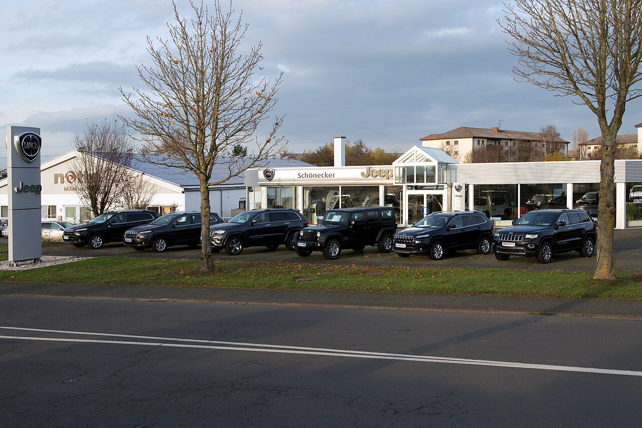 Moderne Garage mat engem verglaste Showroom an Autoen déi um Vordéif parken