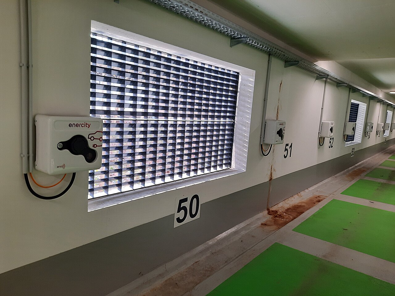 Charging unit mounted on a bare concrete wall inside an underground car park