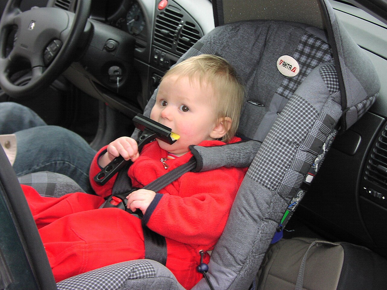 Rear-facing infant car seat strapped onto a vehicle's rear bench