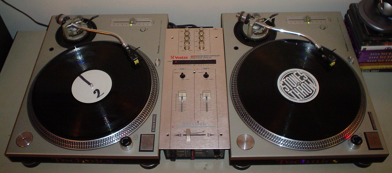Two direct-drive turntables flanking a small battle mixer on a flat surface