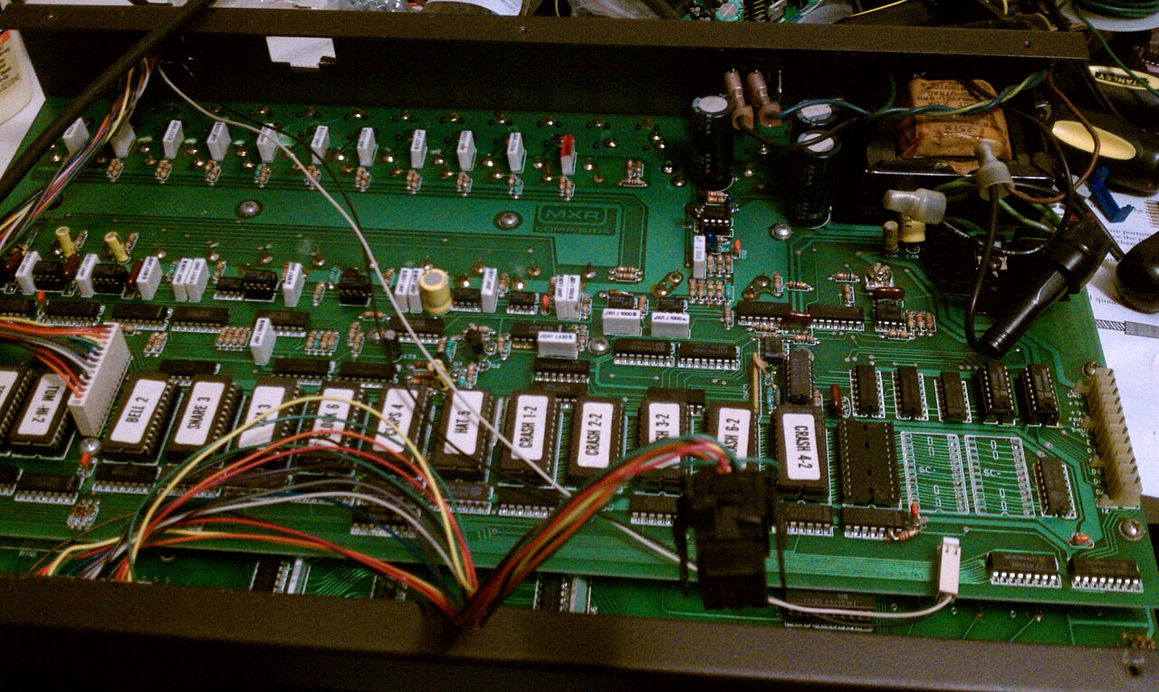 Opened drum machine revealing its circuit board and internal wiring
