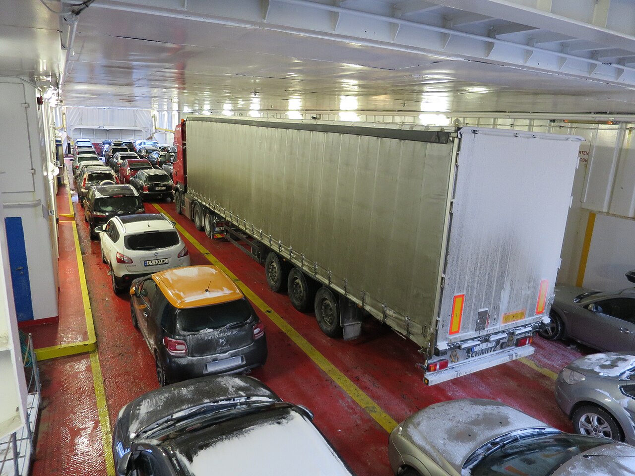 Cars and a lorry packed closely together on a ferry's main vehicle deck