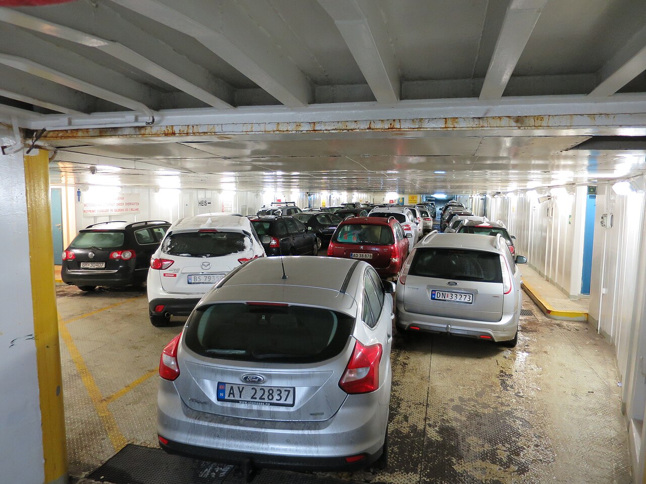 Passenger cars parked in tight lanes on a ferry's lower vehicle deck