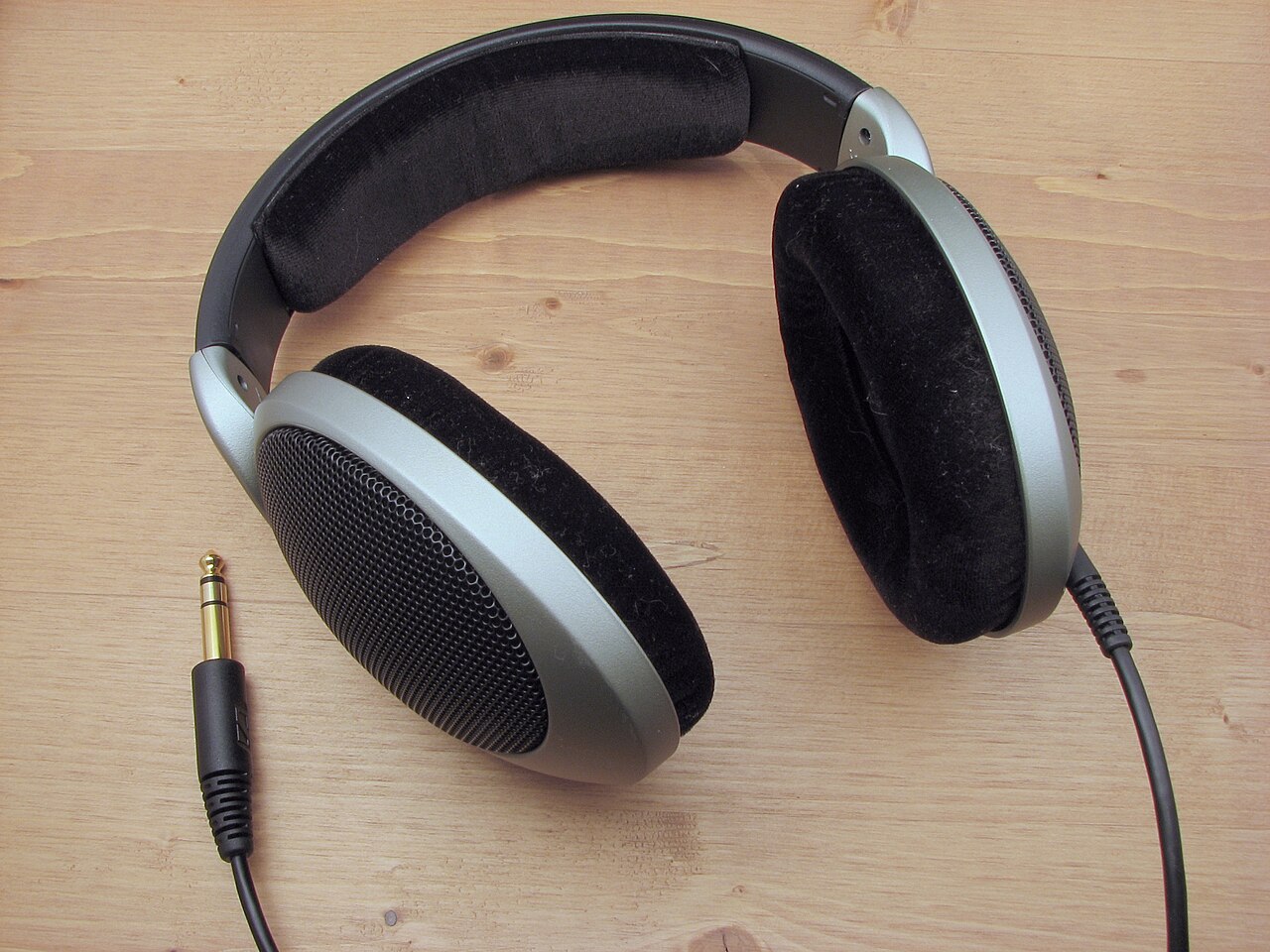 Open-back circumaural headphones with velour earpads resting on a pale surface