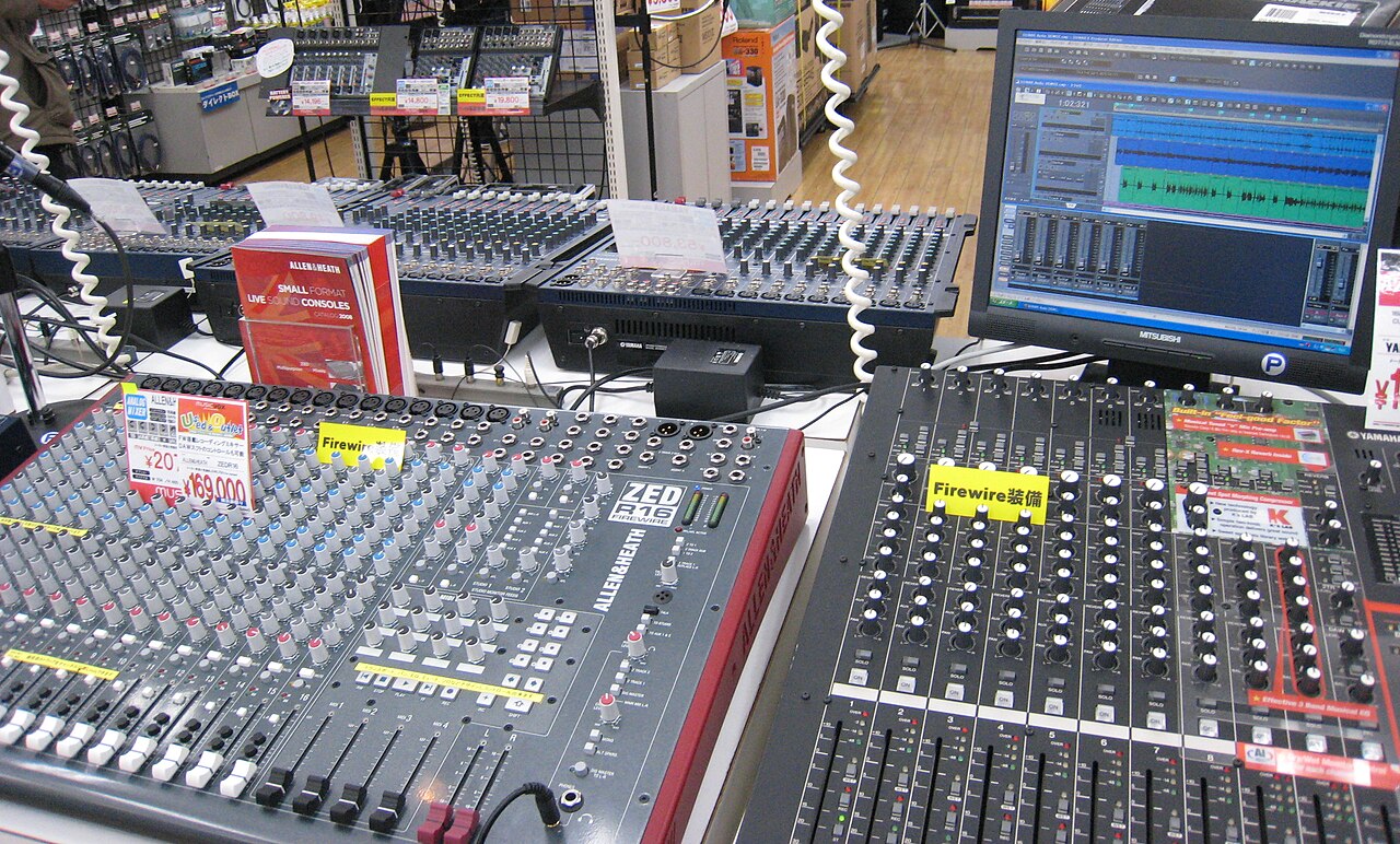 Several small mixers stacked together with their knobs and faders facing the camera
