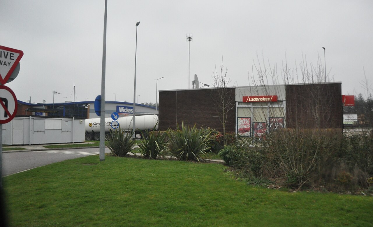 Service area car park with parked cars and a low services building behind