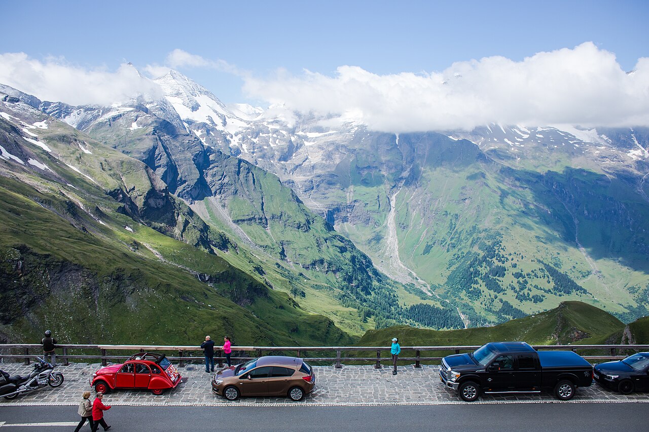 Alpine toll road winding between rocky slopes under a broad sky