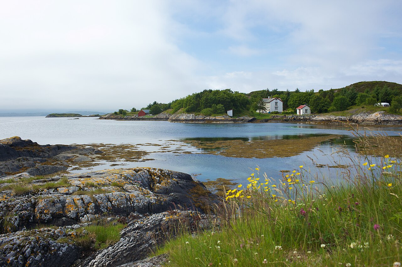 Rocky island and causeway road beside grey Norwegian coastal water