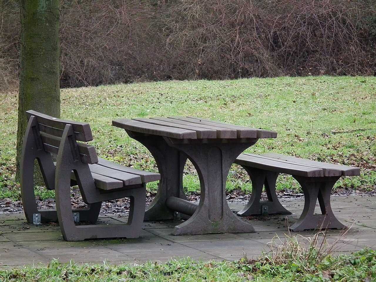Rest area with picnic benches and trees beside a motorway carriageway