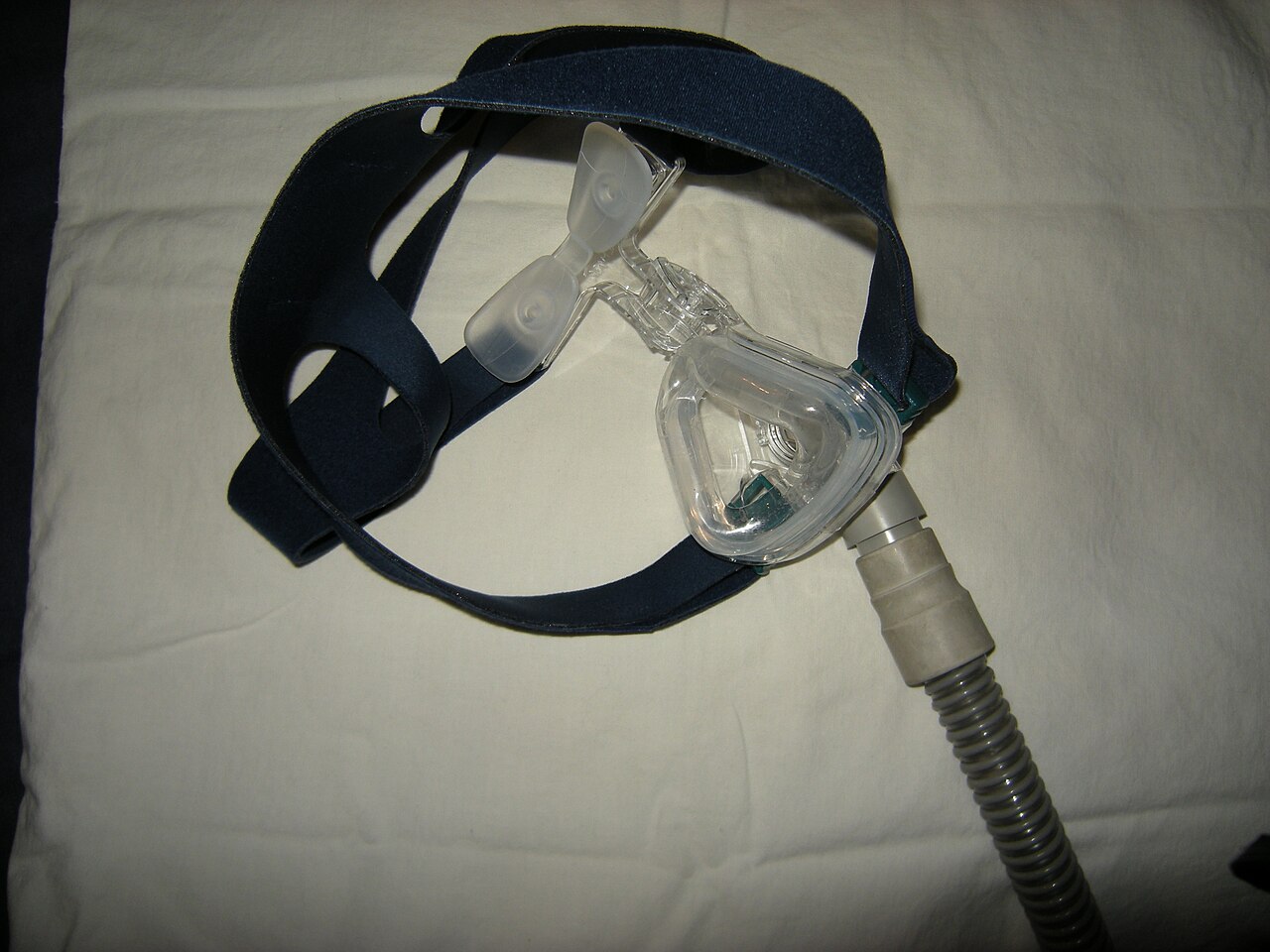 Nasal CPAP mask with forehead tabs and headgear straps laid on a plain surface