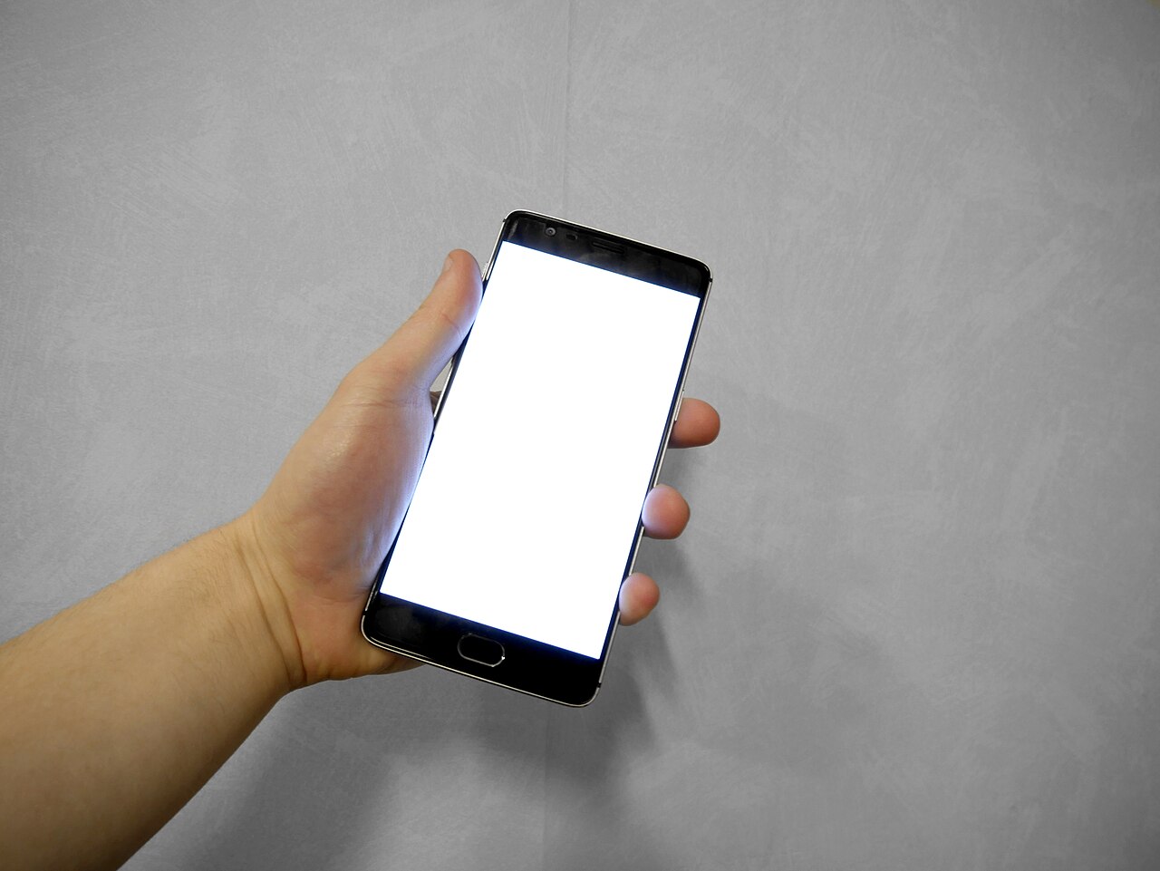 Mano che tiene uno smartphone il cui schermo è completamente bianco e vuoto