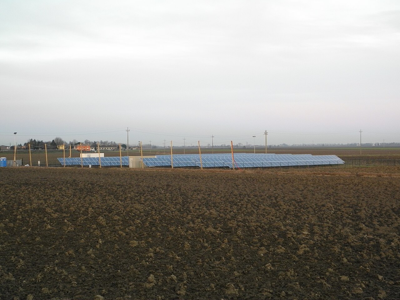Solar panels in long parallel rows across flat farmland