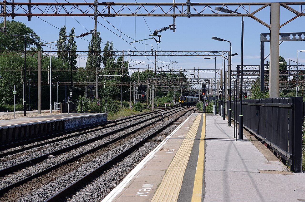 View along a railway platform with a commuter train standing in the distance