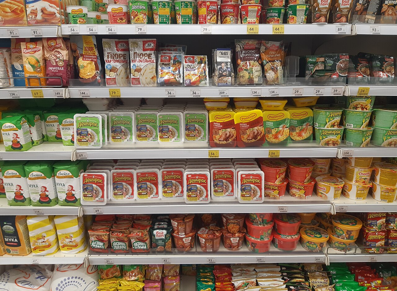 Packets of instant noodles and other packaged products on a shop shelf
