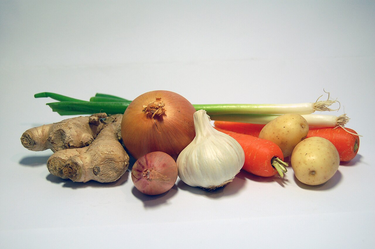 Assorted unwashed root vegetables laid out side by side