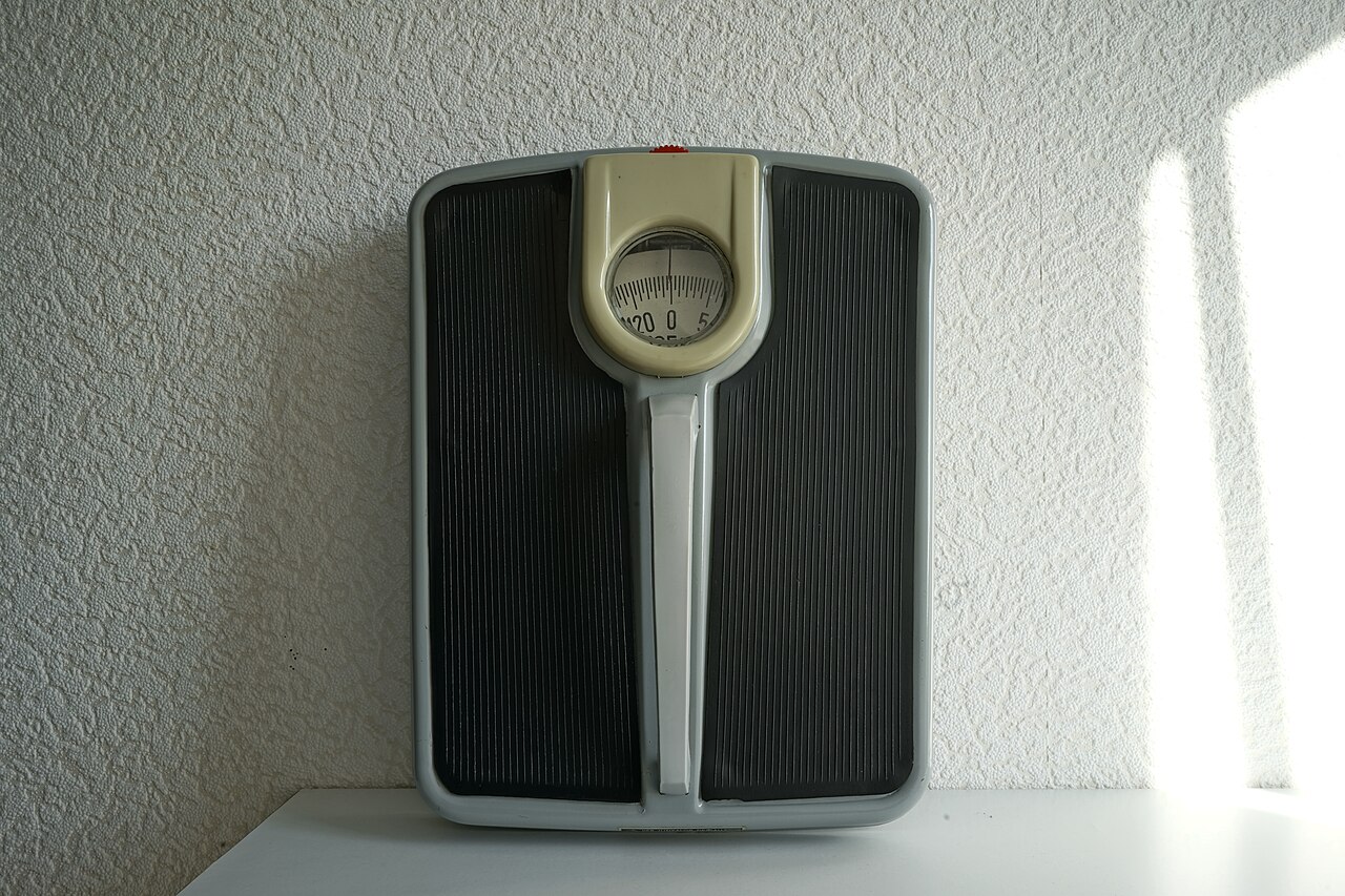 Front of a mechanical personal scale with a rotating dial marked to 125 kilograms