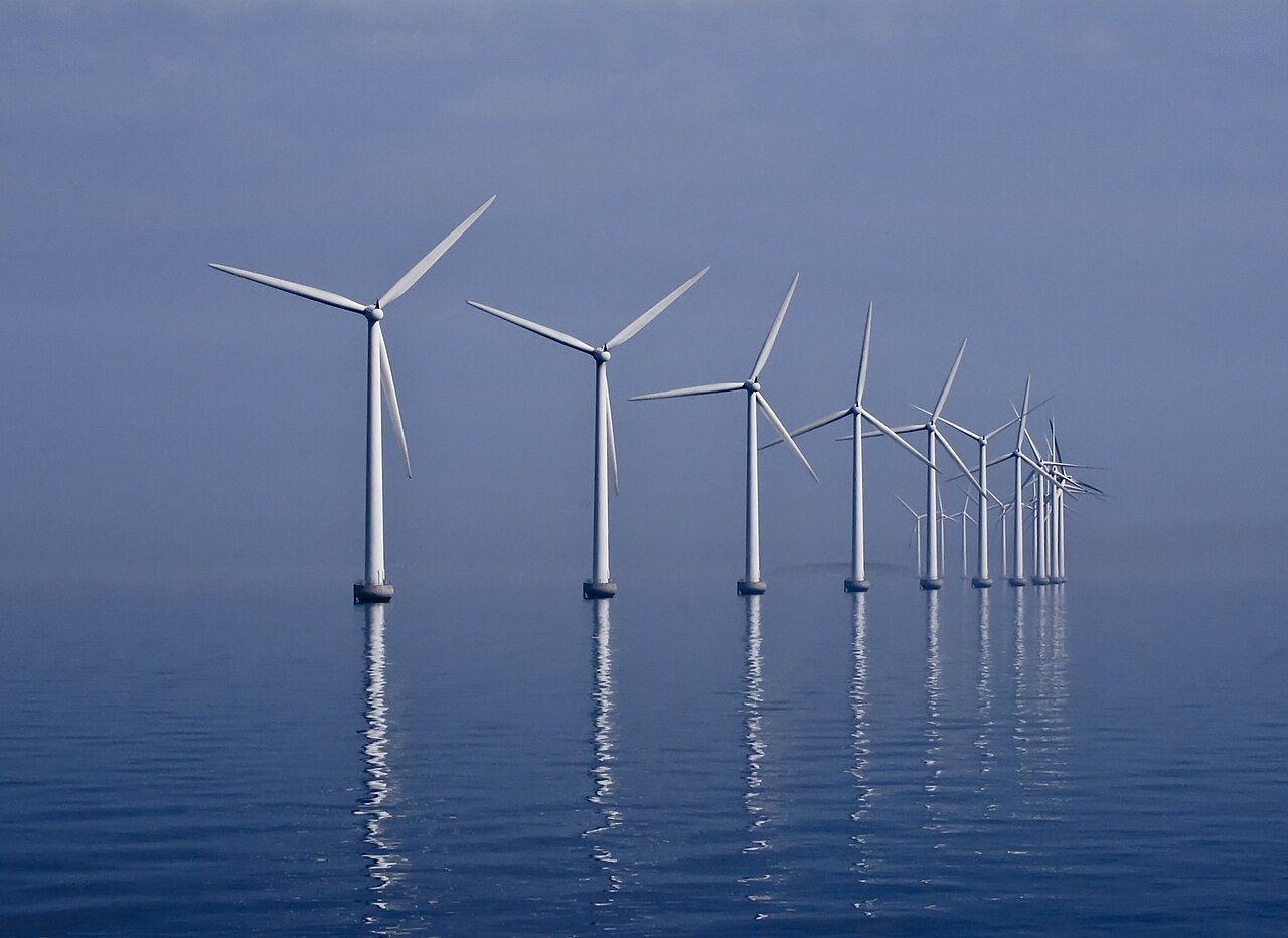 Curved row of offshore wind turbines standing in open water